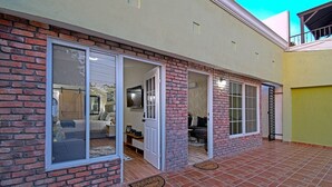 A brick exterior with sliding glass doors leading to a living area with a sofa and a dining table. - Estudio Perfecto Ubicación Ideal (La Paz)