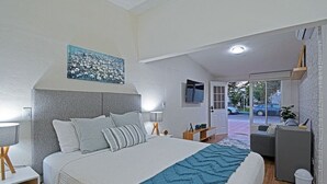 A modern bedroom with a large bed, a painting above the bed, a desk, and a view of the outside. - Estudio Perfecto Ubicación Ideal (La Paz)