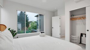 Ein Schlafzimmer mit großem Fenster, einem Bett, einem Schrank und einem kleinen Tisch.