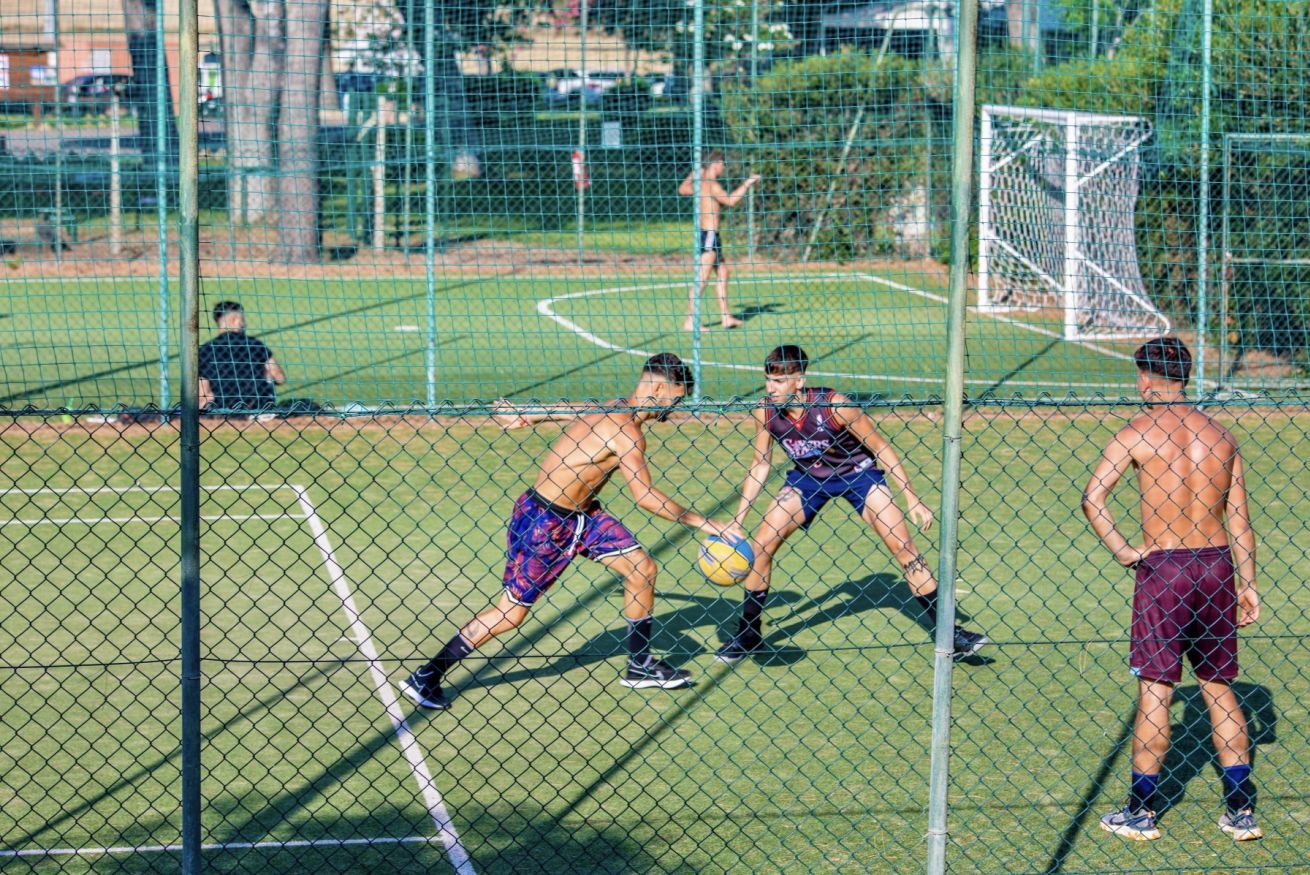 Una cancha deportiva con red, portería y jugadores.