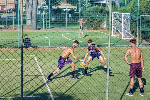 Una cancha deportiva con red, portería y jugadores.