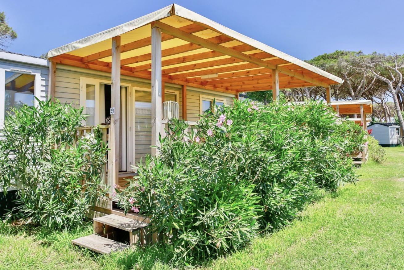 Une maison de plain-pied dotée d’un porche abrité, entourée d’une végétation luxuriante et d’un petit jardin.