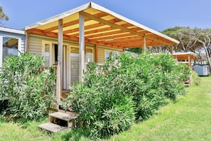 Una casa de un piso con porche cubierto, rodeada de abundante vegetación y un pequeño jardín.
