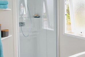 A glass-enclosed shower area with a visible showerhead and a towel rack with a blue towel.