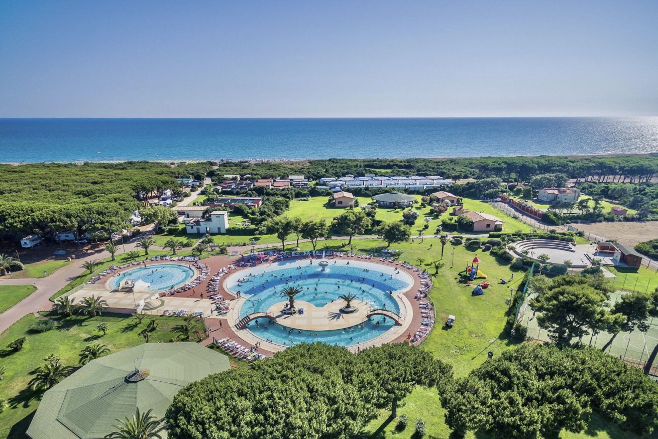 A resort with multiple swimming pools, a large central pool, and a view of the sea.