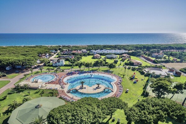 A resort with multiple swimming pools, a large central pool, and a view of the sea.