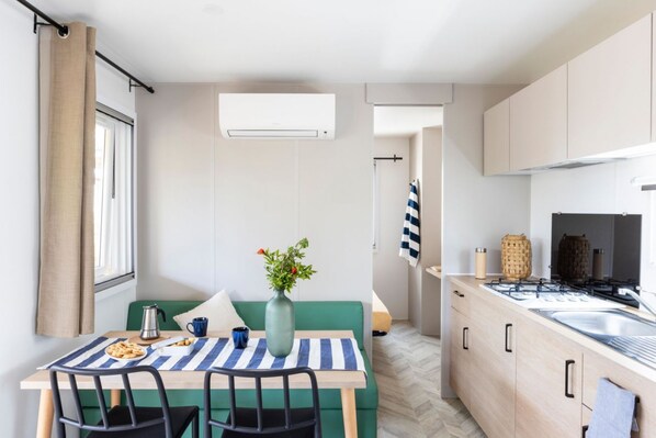 A compact kitchen with a dining area, featuring a striped tablecloth, a vase with flowers, and a view of the adjacent room.