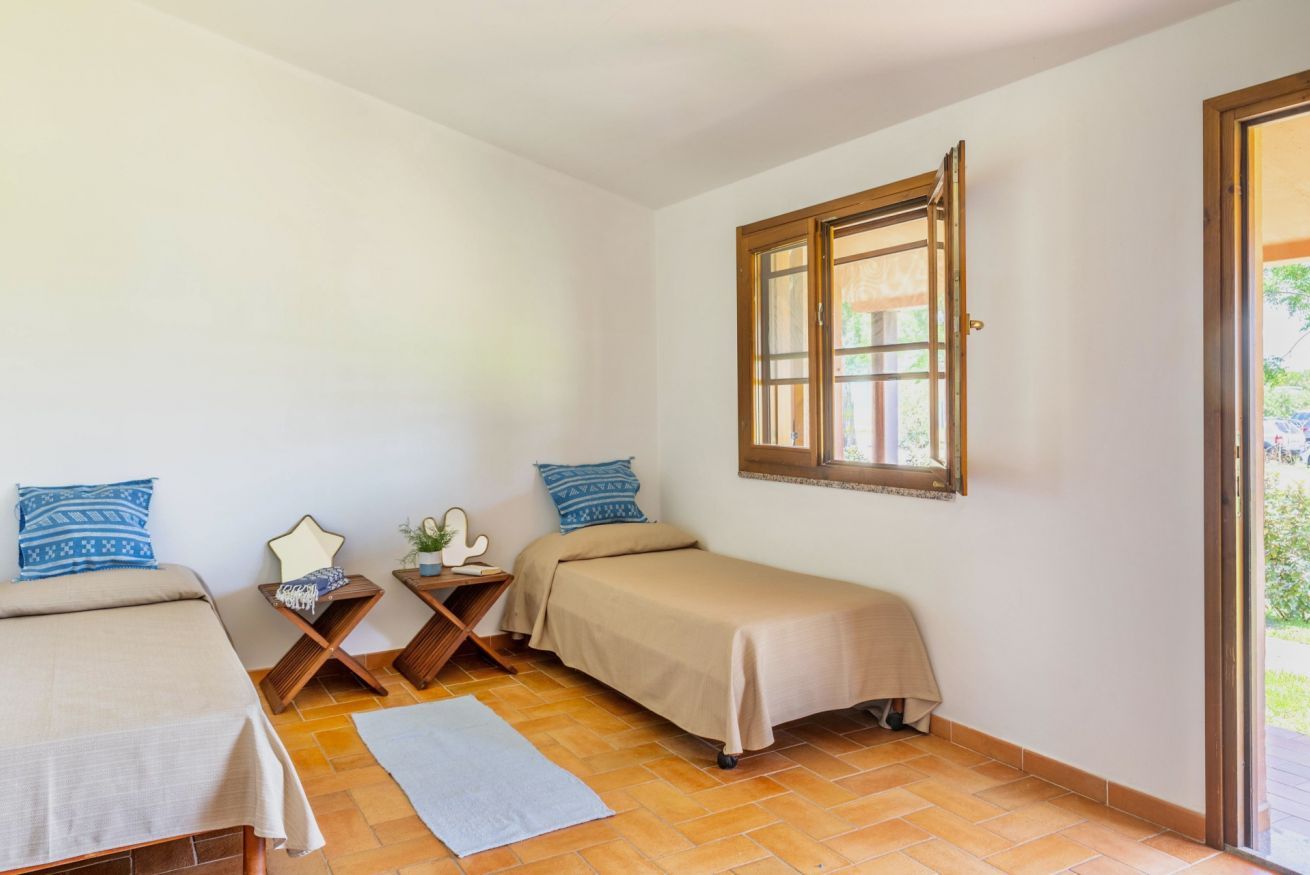 Une chambre avec deux lits, une fenêtre et une petite table sur laquelle est posée une plante.
