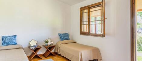 Una habitación con dos camas, una ventana y una mesita con una planta.