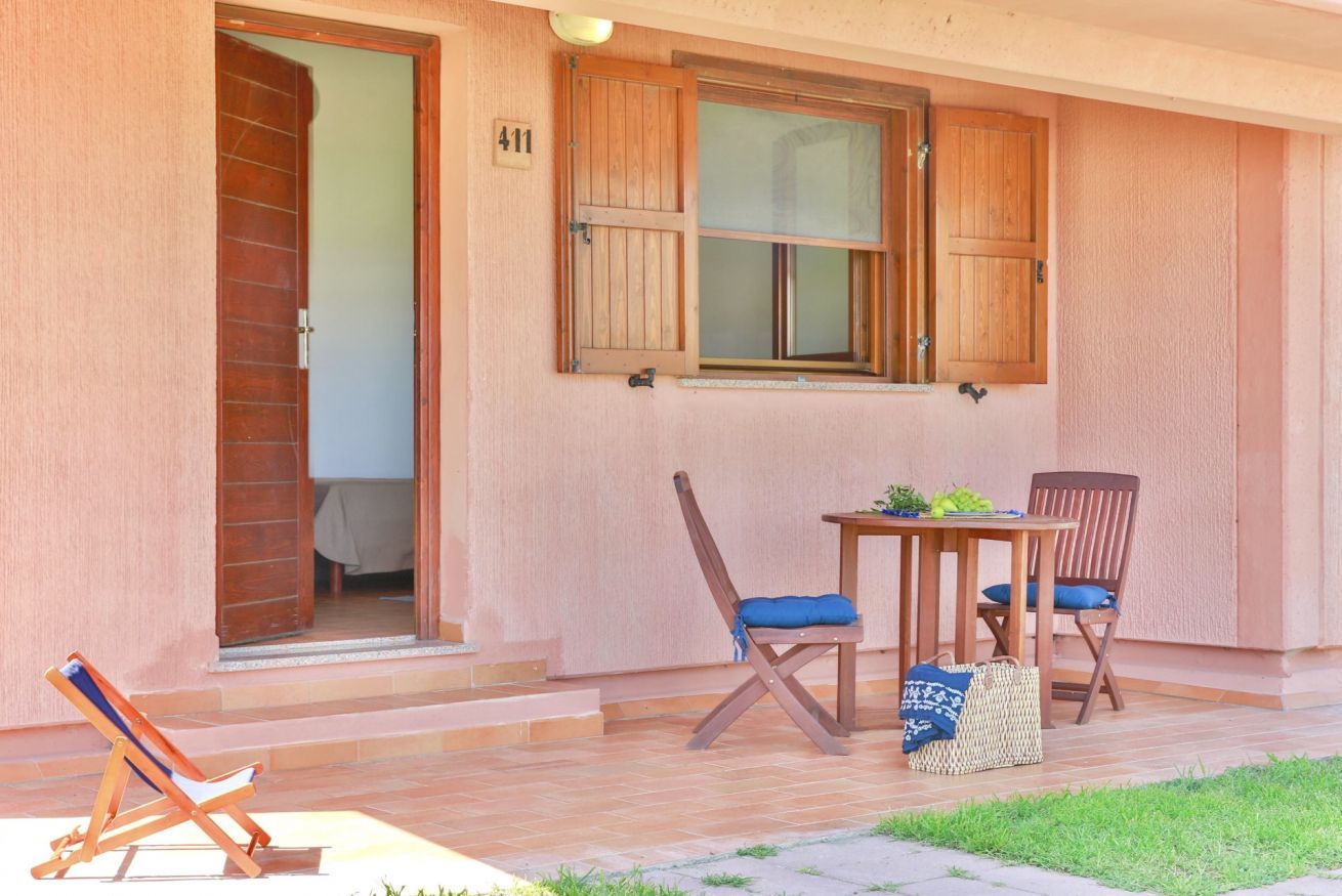 Ein Gebäude mit Holztür, Fensterläden, einem Tisch mit Stühlen und einem Liegestuhl.