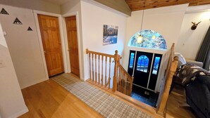 A wooden staircase leading to a room with a view of the sea through a glass door. - Valley Home with Game Room, Walking Distance to Narrow Gauge Trails & Restaurant (Carrabassett Valley)