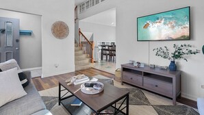 A modern living room with a sofa, coffee table, and a flat-screen TV mounted on the wall.