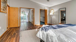 A bedroom with a bed, a ceiling fan, a walk-in closet, and a view of the outdoors.