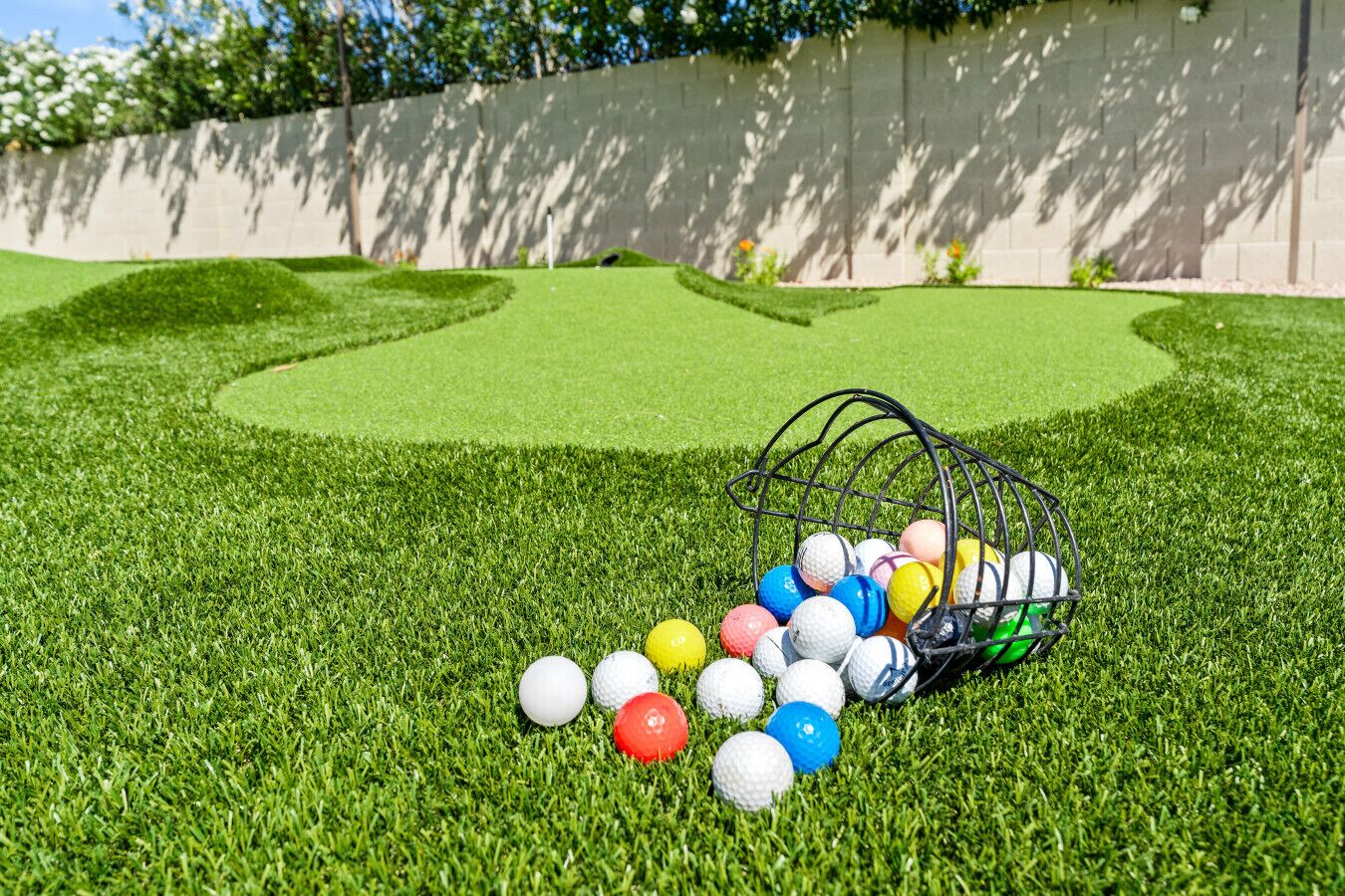 A golf course with a putting green and a basket of golf balls.