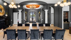 Comedor con una larga mesa, sillas negras y un candelabro.