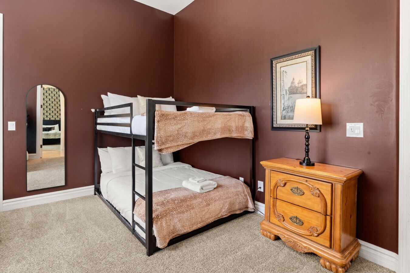 Une chambre avec un seul lit superposé, une commode en bois et un tableau encadré au mur.