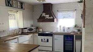 A kitchen with white brick walls, wooden cabinets, a wooden countertop, a stove, a refrigerator, and a window with a view. - Charming cottage in Girard with WiFi and AC - perfect getaway (Girard)