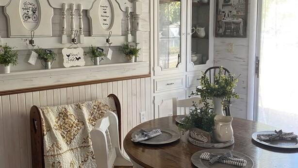 A dining area with a wooden table, white chairs, a chandelier, and decorative wall panels. - Charming cottage in Girard with WiFi and AC - perfect getaway (Girard)