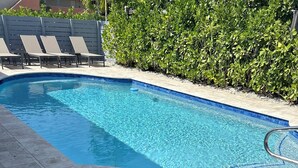 A swimming pool with clear blue water, surrounded by a tiled deck and a row of lounge chairs. - 3 bedroom 2 bath heated pool, 1 block to Wilton Dr close to Beaches
  Sleeps 6 (Wilton Manors)