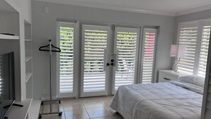 A bedroom with a bed, a nightstand, a lamp, a wardrobe, and a trolley. - 3 bedroom 2 bath heated pool, 1 block to Wilton Dr close to Beaches
  Sleeps 6 (Wilton Manors)