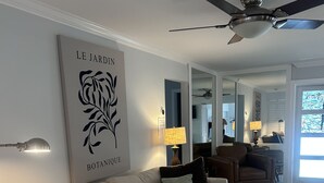 A living room with a sectional sofa, a ceiling fan, and a wall-mounted artwork. - 3 bedroom 2 bath heated pool, 1 block to Wilton Dr close to Beaches
  Sleeps 6 (Wilton Manors)