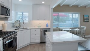 Una cocina moderna con armarios blancos, estufa de acero inoxidable y una isla grande con encimera de mármol.