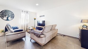 Una sala de estar moderna con un sofá, una butaca, un televisor y una lámpara.