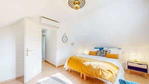 Un dormitorio con cama, mesita de noche y puerta abierta que da a otra habitación.