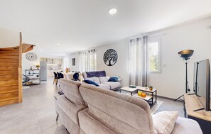 A modern living room with a sofa, a coffee table, and a dining area with a table and chairs.