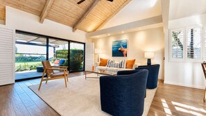 A modern living room with a large window, a sofa set, and a dining area.