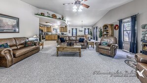 Un amplio salón con chimenea, muebles de cuero y ventilador de techo.