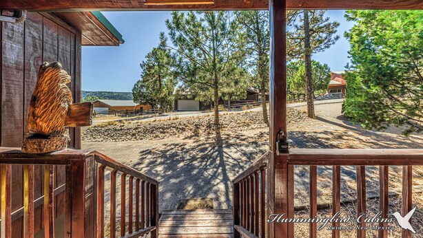 Una cabaña de madera con una escalera que lleva a una terraza con vistas a la playa y el bosque.