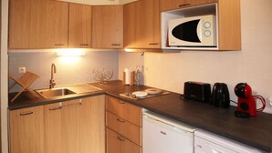 Una cucina compatta con mobili in legno, un forno a microonde, un tostapane e una macchina da caffè.