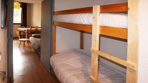 Una camera con letto a castello in legno, un letto singolo e un tavolo con sedie.