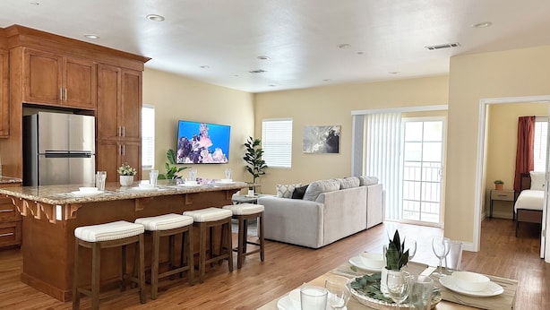 A modern kitchen with a central island, wooden cabinets, and a built-in refrigerator. - Disneyland Getaway Tri-level Gated Townhome (Placentia)