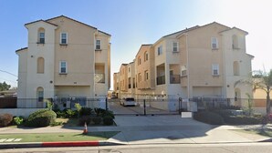 A residential building with multiple floors, balconies, and a gated entrance. - Disneyland Getaway Tri-level Gated Townhome (Placentia)