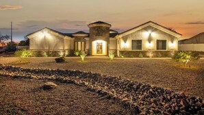 A two-story house with a stone facade, a central entrance, and a driveway leading to the front door. - The Grand Oasis – Resort-Style Retreat w/ Sauna, Cold Plunge, Mini Golf & Volleyball (Goodyear)
