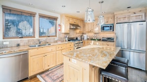 A modern kitchen with wooden cabinets, stainless steel appliances, and a granite countertop.