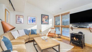 A cozy living room with a sofa, coffee table, fireplace, TV, and framed pictures on the wall.