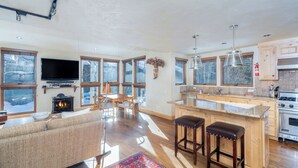 A spacious living area with a fireplace, a television, and a large window overlooking a snowy landscape.