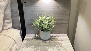 A modern bedside table with a potted plant, a drawer, and a built-in shelf.