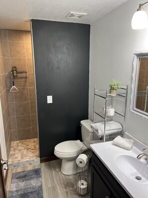 A bathroom with a toilet, sink, and shower area.