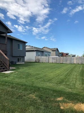 A residential area with multiple houses, a well-maintained lawn, and a wooden fence.
