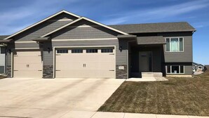 A two-story house with a garage, a front porch, and a well-maintained lawn.
