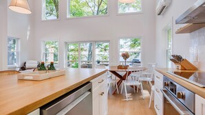Une cuisine moderne dotée de grandes fenêtres, de meubles blancs et d’un plan de travail en bois.