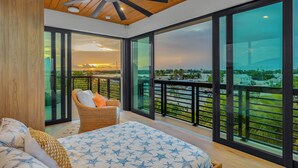 A modern bedroom with a large bed, a ceiling fan, and a balcony with a city view. - New!Luxurious & spacious waterfront 4 bedroom house in Marathon with endless fun (Marathon)