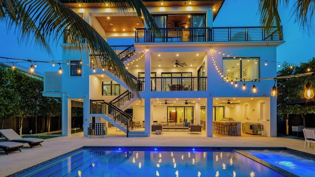 A two-story modern house with a pool, outdoor seating, and string lights. - New!Luxurious & spacious waterfront 4 bedroom house in Marathon with endless fun (Marathon)