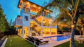 A multi-story modern house with a swimming pool, outdoor seating, and a well-lit balcony. - New!Luxurious & spacious waterfront 4 bedroom house in Marathon with endless fun (Marathon)