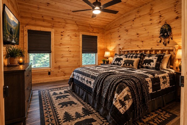 Un dormitorio acogedor con una cama grande, un ventilador de techo y vistas al exterior.