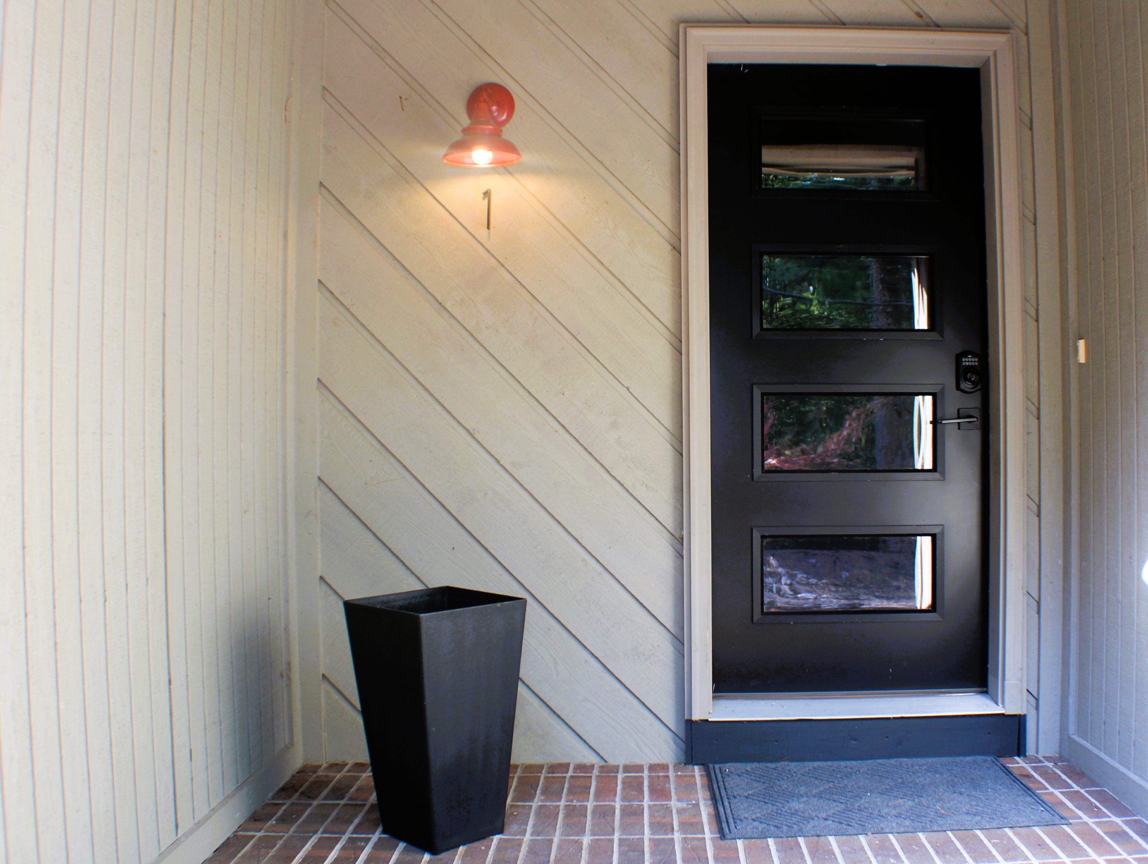 A black door with three glass panels and a red light above it.